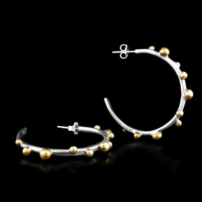 These hoop earrings are circular in shape with round brass accents throughout varying in size. Each earring is stamped with .925 on the back.