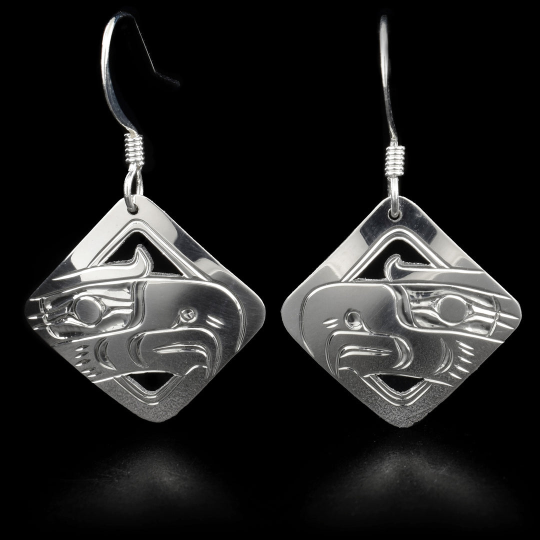 These eagle earrings are diamond-shaped. Each earring has the head of an eagle facing inward with a long, wide beak. Parts of the earring have been cut out for depth.