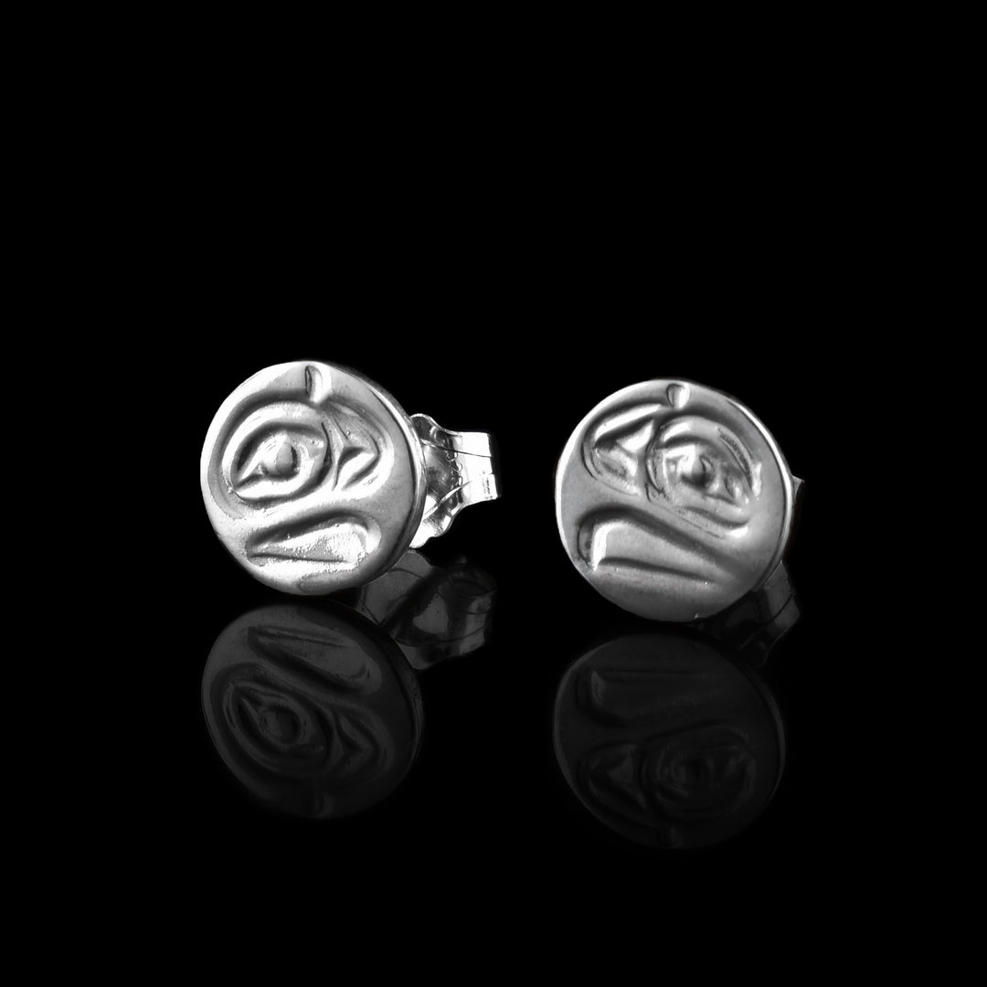 These small silver stud earrings have a small, circle shaped and there is a side profile depiction of the Raven's head cast into them. The eye is large and its curved beak is detailed on its surface.