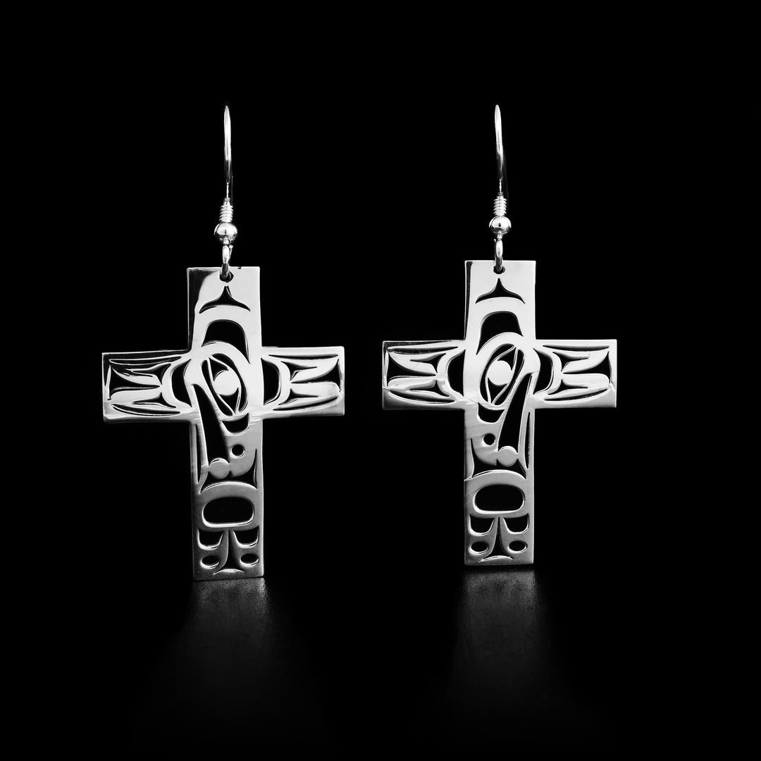 These sterling silver earrings hold the shape of a cross. The Raven holding the Sun is carved on the earrings. 