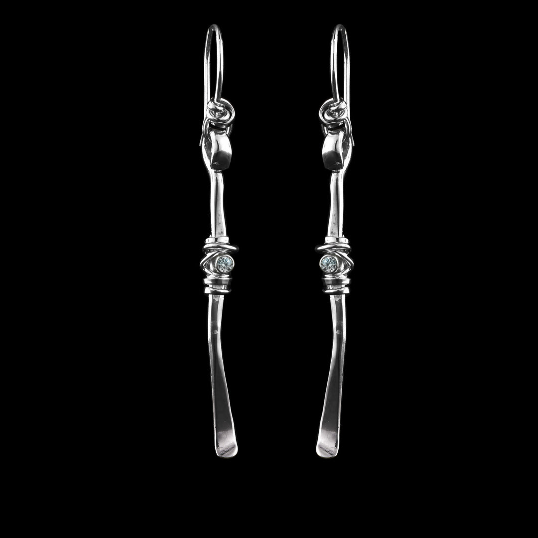 These drop, cubic zirconia earrings have long sterling silver rods attached to the hooks. On the rods are cubic zirconia gemstones with silver wrapped around them.