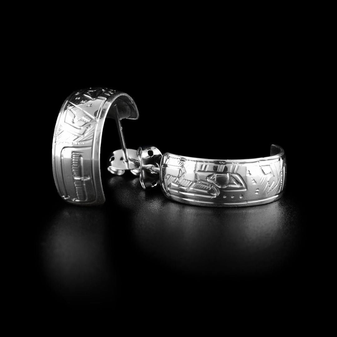 These wide hoop earrings are made from sterling silver and have wide bands curved into half hoop stud earrings. The head of the eagle is carved into the bands with its beak facing the studs and there is a wing detail behind the head.