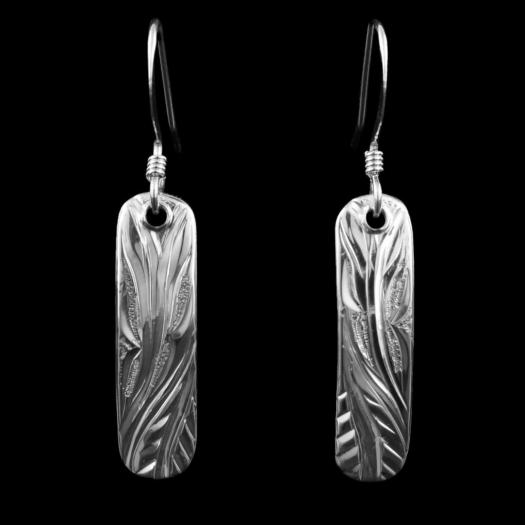 These sterling silver flower earrings have long, thin and rectangle shaped hangs. There are wavy designs carved into the hangs depicting floral designs.