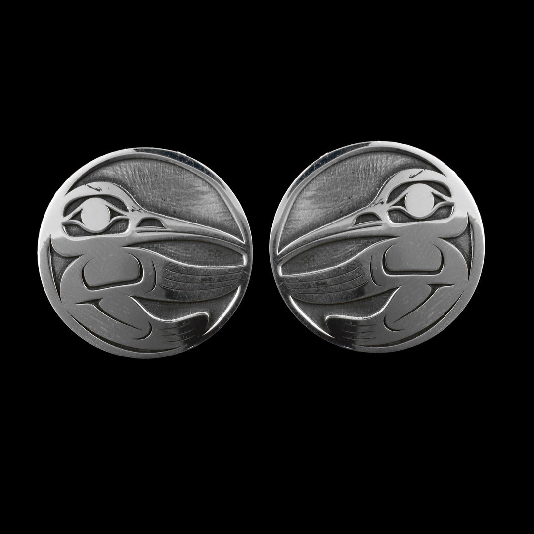These large stud earrings are made from sterling silver and have a circle shape. The Hummingbird legend is shown at a side profile in the piece. Its eye, beak, wing and tail are depicted.