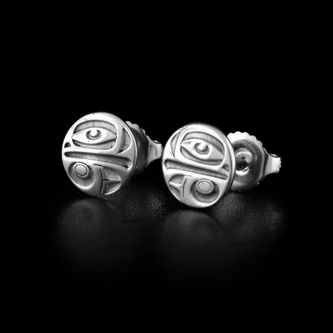 These Eagle stud earrings are made from sterling silver and have a small, circle shape. The Eagle legend is shown at a side profile and the carvings are deep in the surface. Its eye is at the top with its beak and the bottom half is a wing design.