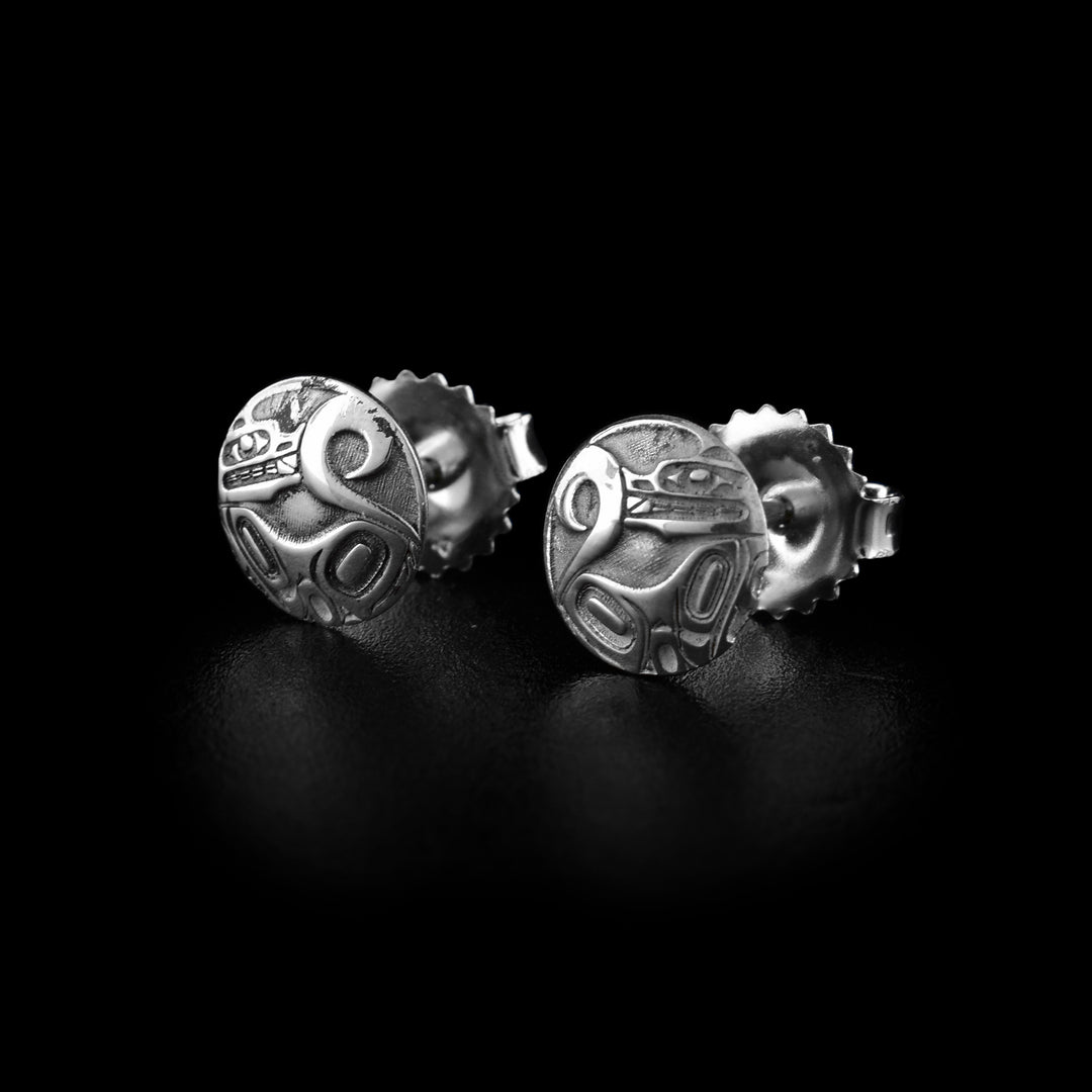 These Wolf stud earrings are made from sterling silver and have a small, circle shape. Wolf legend is shown at a side profile and the carvings are deep in the surface. Its body extend across the studs with its head at one end looking back at its tail at the other end.