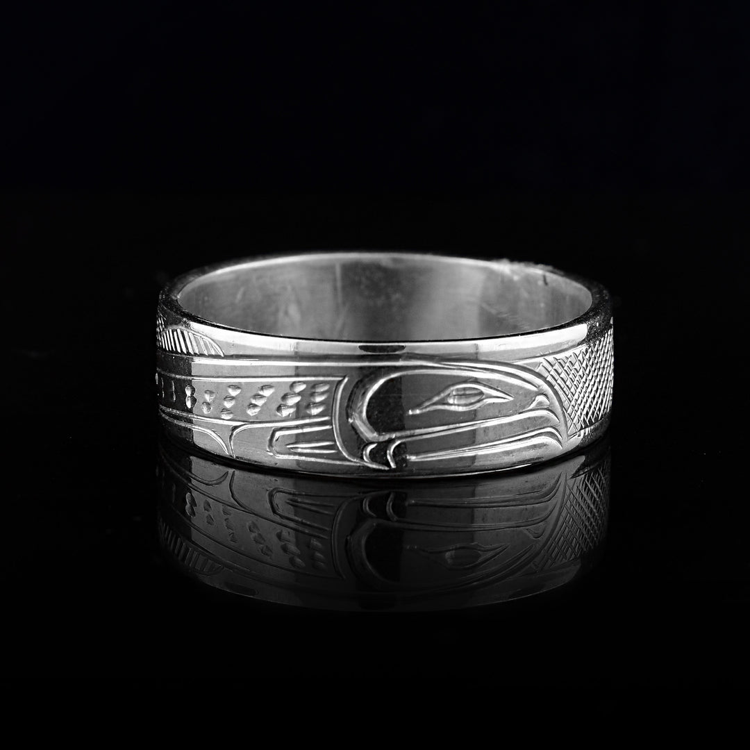 This sterling silver band ring has a single, sterling silver band with a depiction of the Salmon carved into it. The legends full body is shown at a side profile and there are cross hatching design in the background of the piece.