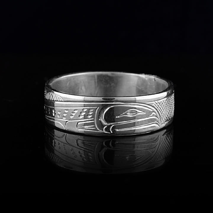 This sterling silver band ring has a single, sterling silver band with a depiction of the Salmon carved into it. The legends full body is shown at a side profile and there are cross hatching design in the background of the piece.