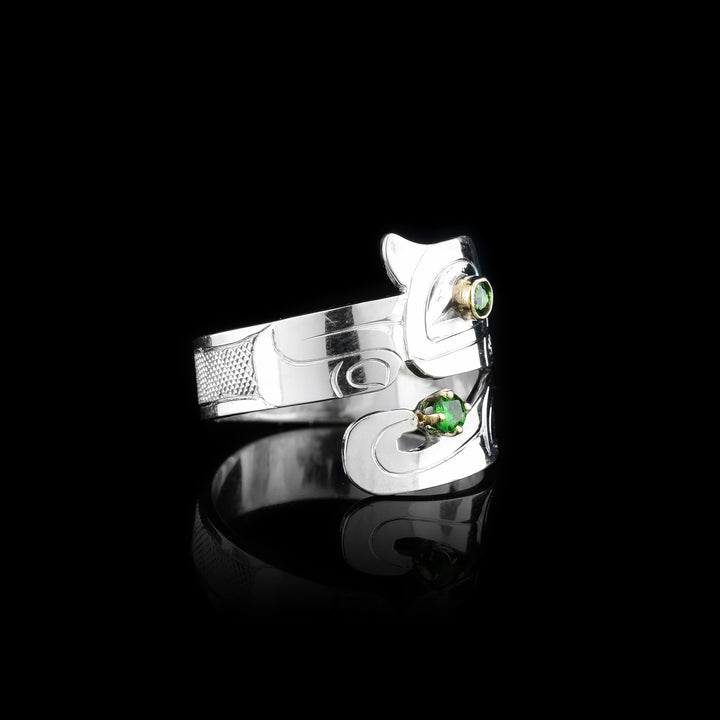 This Otter ring has a wide band that wraps around the finger twice. The top band is carved to depict the head of the Otter and the bottom one depicts its tail. There are green tsavorite gems that are embedded into the eye of the legend and in the center of its tail. There are 14K gold highlights around the eye of the Otter.