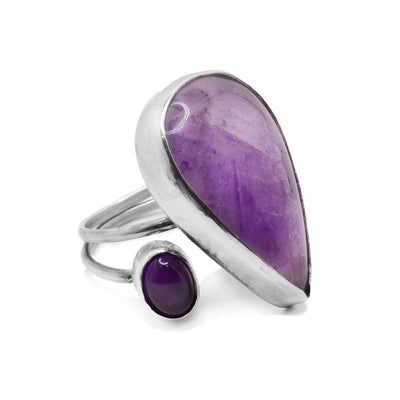 This amethyst ring has a large, teardrop shaped amethyst in the center with a smaller, oval one to its left. The band is dainty and wraps around twice in the back.