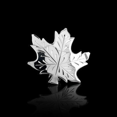 This maple leaf pin is made from sterling silver and has been cutout to depict a maple leaf. There are carvings on the surface of the piece that represent the veins of the leaf.