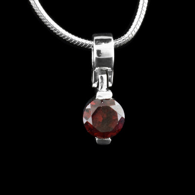 This garnet and silver pendant has a sterling silver bail that attaches with a hinge to the red garnet gem. There are two claws holding the gem at the top and the bottom.