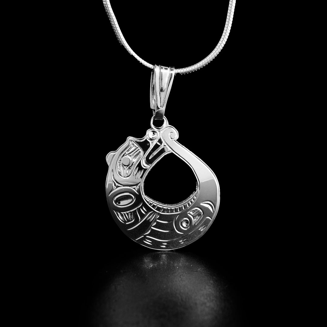 This round Otter pendant is made using sterling silver and is shaped like the Otter curled up on its back. There is a circle cutout in the piece and carvings across the surface of it depicting the Otter.