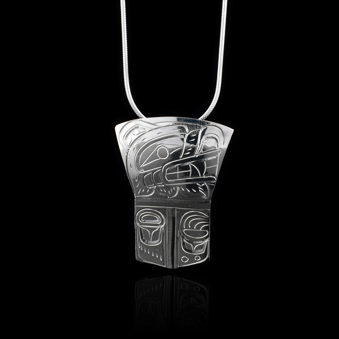This sterling silver Bear pendant has a rectangle shape with the top half of it flaring out to get wider at the top. The pendant represents a Shield and there is a depiction of the Bear legend's head shown at a side profile carved into the top section of the piece. There are claw and paw patterns carved into the bottom half.