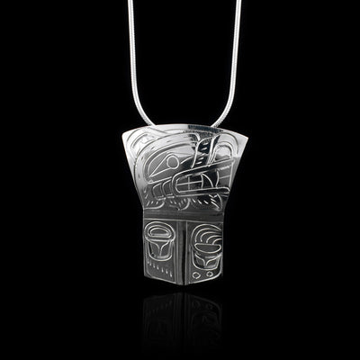This sterling silver Bear pendant has a rectangle shape with the top half of it flaring out to get wider at the top. The pendant represents a Shield and there is a depiction of the Bear legend's head shown at a side profile carved into the top section of the piece. There are claw and paw patterns carved into the bottom half.