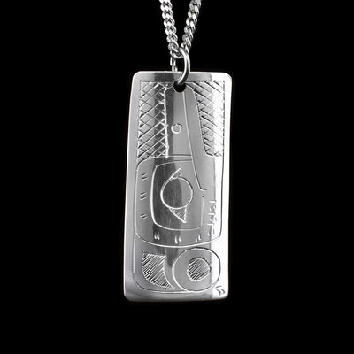 This Hummingbird and Wolf pendant is made from sterling silver and has a wide, rectangular shape to it. This piece is double sided and there is a depiction of the Wolf carved into one side and a depiction of the Hummingbird carved into the other.