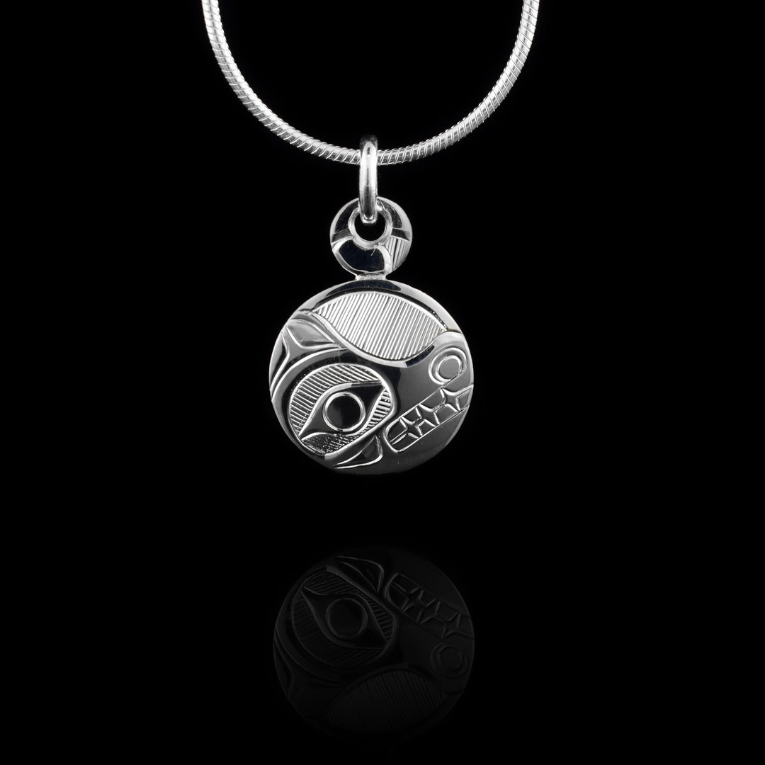 This Bear pendant has a side-view of bear face with teeth showing. Finely carved lines in background. The pendant is circle shaped and there is a smaller circle above the pendant that links to the jump ring.