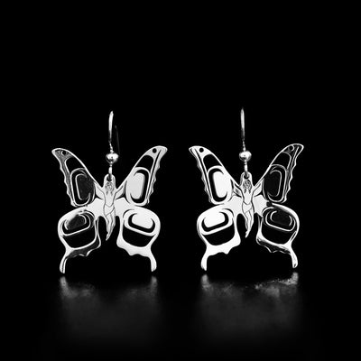 These sterling silver earrings hold the shape of a butterfly with a carved human in the middle of it. 