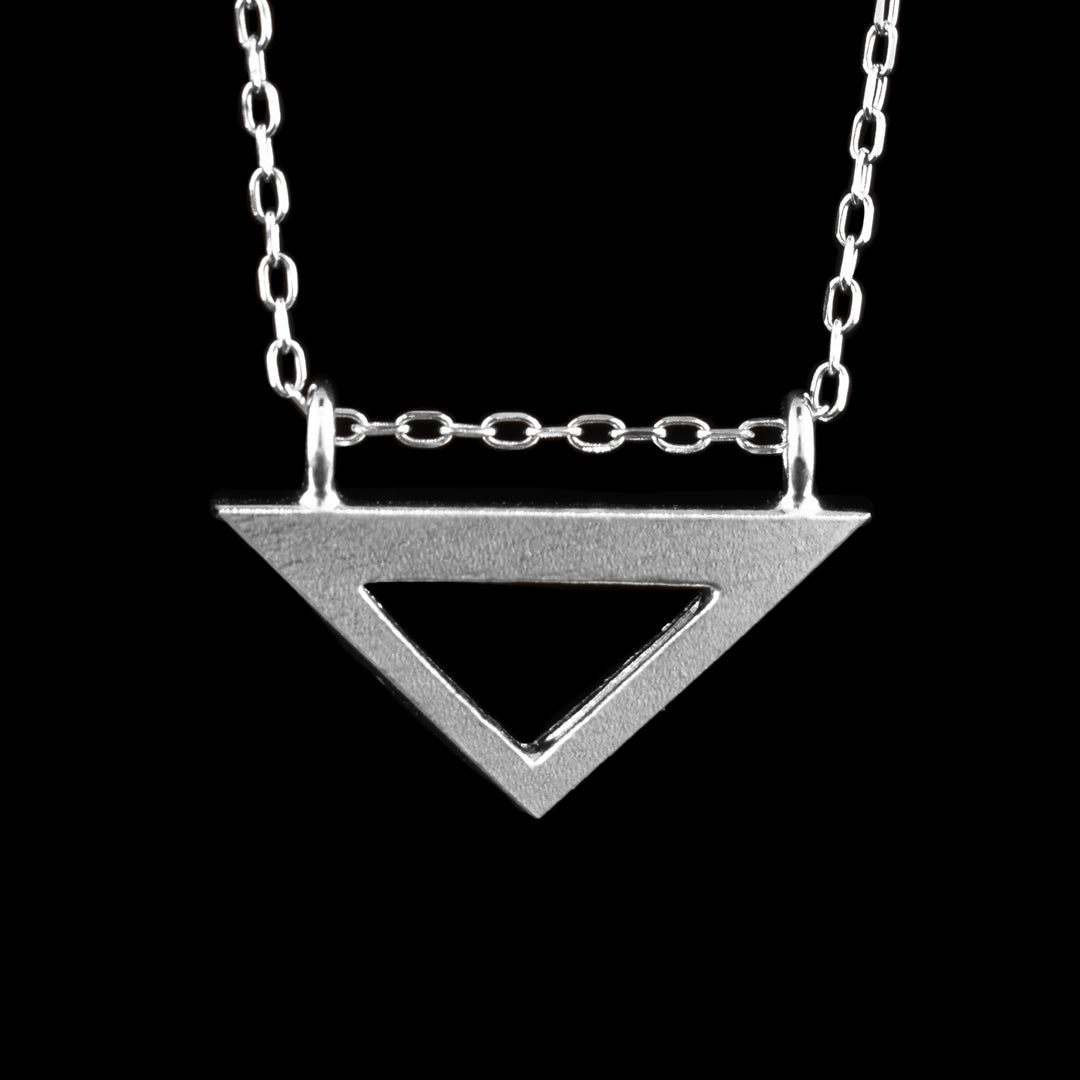 This small triangle pendant is made from sterling silver. There is a short, wide triangle that is upside down and has a triangle shaped cutout in the center of it. There are two rings attached to the ends of the triangle where the chain runs through.