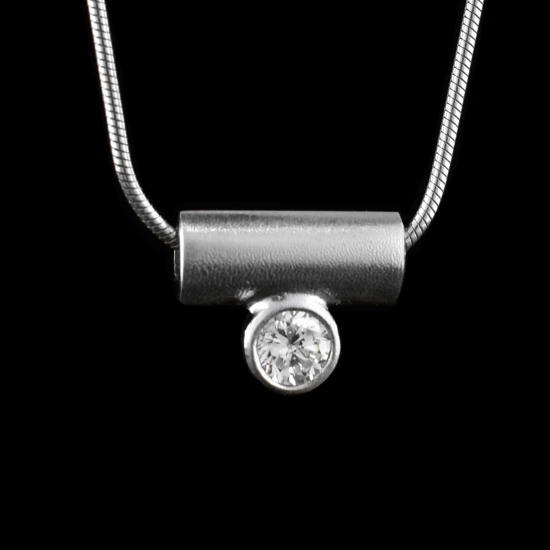 This cubic zirconia diamond pendant has a small, sterling silver cylinder with a bezel set gem resting below it in the center. The necklace chain runs though the cylinder.