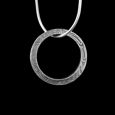 This hoop necklace pendant has been made from sterling silver and has a single hoop made up of a flat, thin band. There are depictions of the Eagle and the Wolf legend carved into the surface of the band. The legends are facing away from each other in a "yin-yang" fashion.