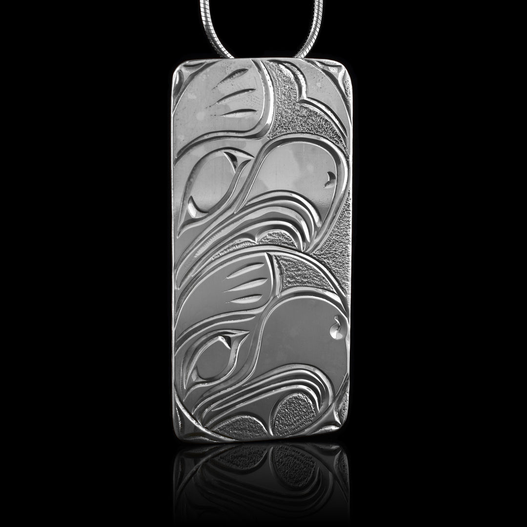 This sterling silver Eagle pendant has a large rectangle shape. The head of the Eagle is depicted at a side profile in side a "womb" with a larger head representing the mother above it.