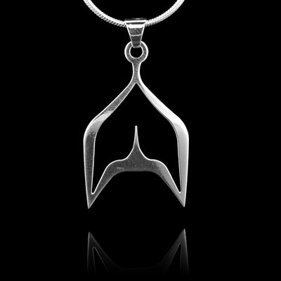 These sterling silver pendants have a unique whale tail shape with a cutout in the centre. The piece depicts a Haida Gwaii character.