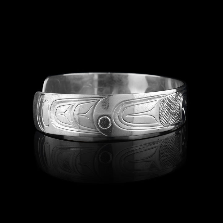 This sterling silver cuff Thunderbird bracelet has a single band what a gap in the back. The head of the Thunderbird is carved in the center of the band and has fierce beak and eye details. There are cross hatching patterns detailing its wings which extend on both sides of the band.