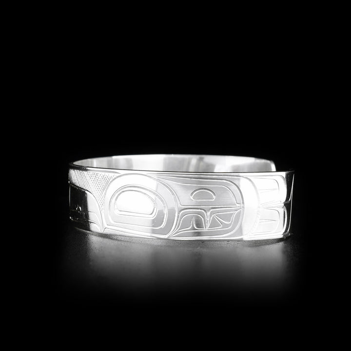 This sterling silver cuff bracelet has a single band with a gap in the back. There is a depiction of the Raven carved into the surface of the band.