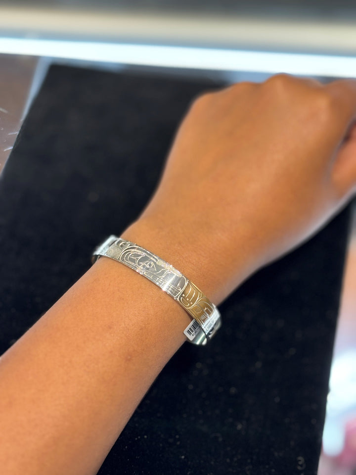 The photo shows a close up of a model's hand while wearing the cuff bracelet.
