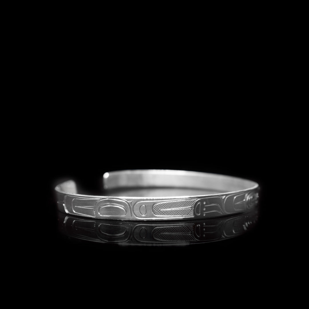 This thin sterling silver cuff bracelet has a depiction of the Raven carved into the surface of the band.