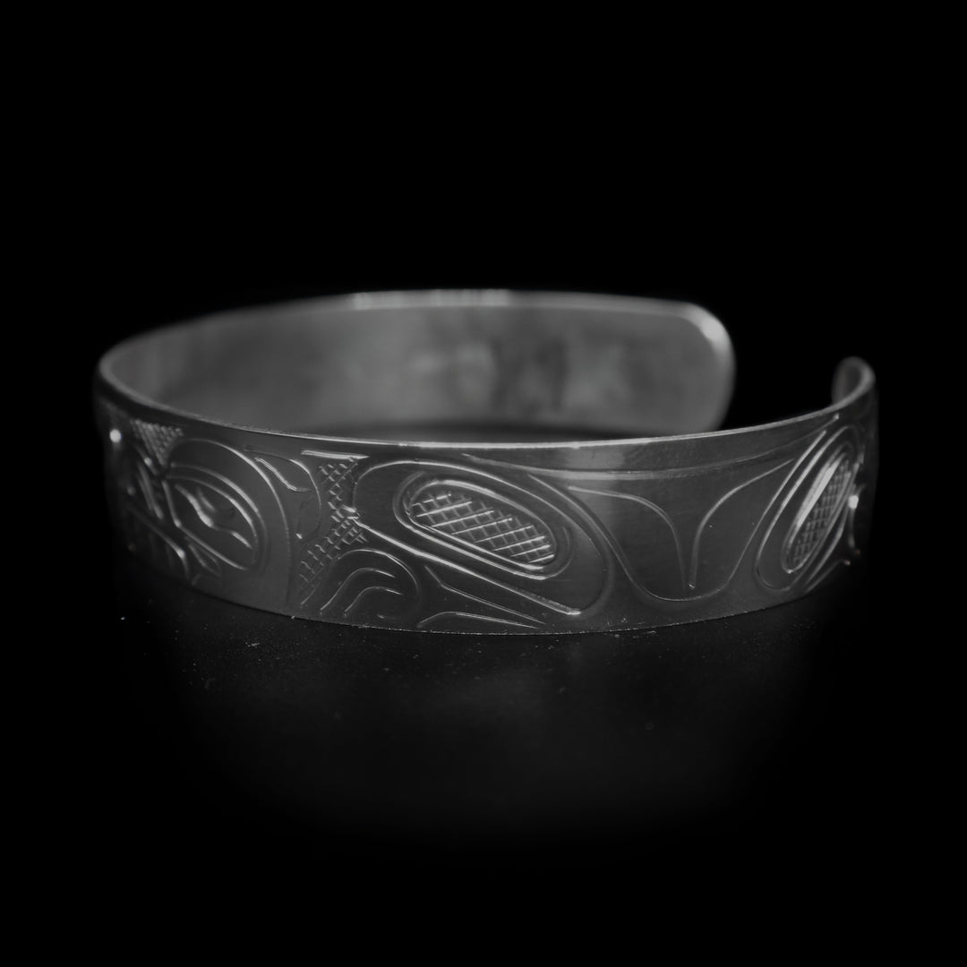This large Bear bracelet cuff has a sterling silver band with a gap in the back. There are two depictions of the Bear carved into the band. The heads meet in the center of the band and their bodies are depicted on either side of the band.