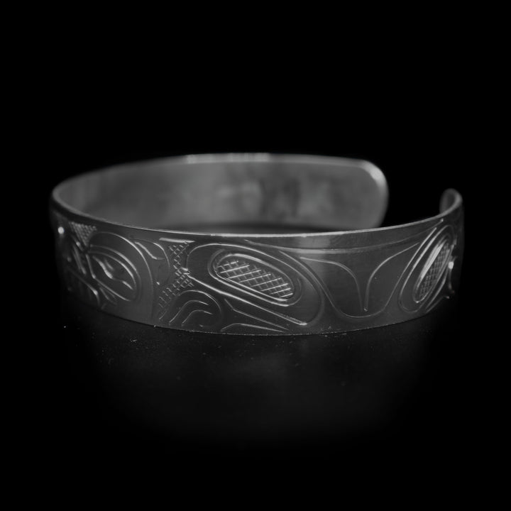 This large Bear bracelet cuff has a sterling silver band with a gap in the back. There are two depictions of the Bear carved into the band. The heads meet in the center of the band and their bodies are depicted on either side of the band.