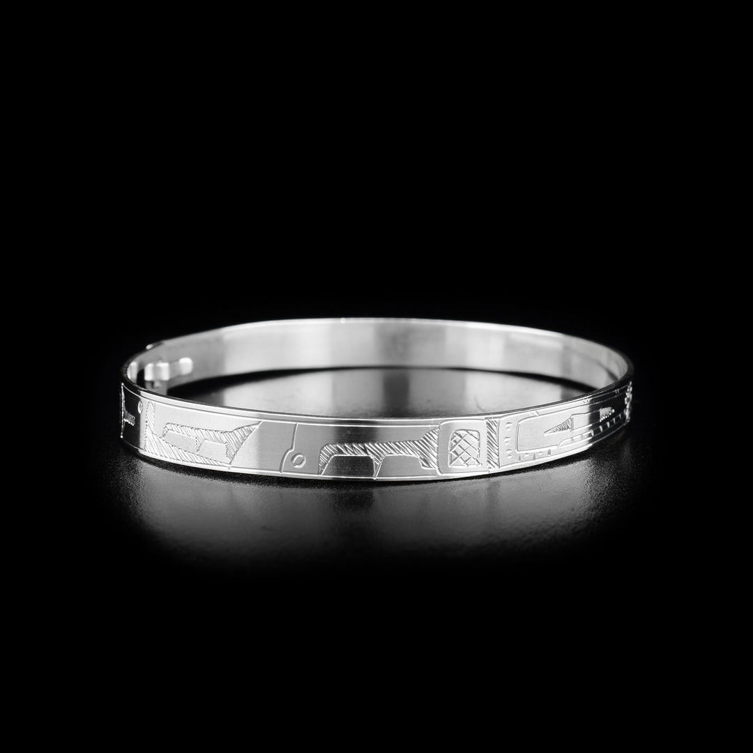 This Orca bracelet is made from sterling silver. The bracelet has a thin band with two depictions of the Orca carved into the surface of it.