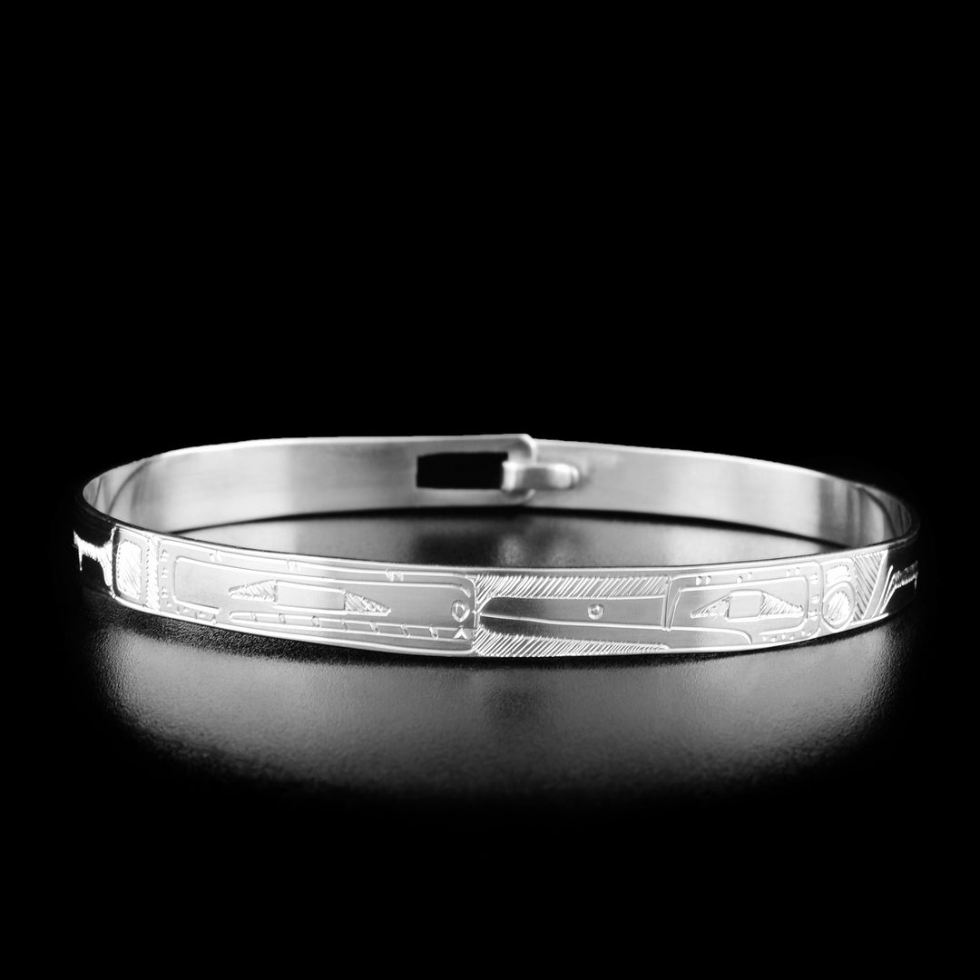 This clasp bracelet has the profile of the head of an orca and the head of a hummingbird facing each other in the center of the bracelet.