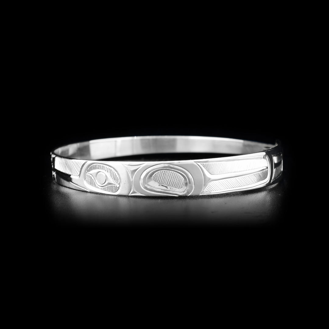 This Hummingbird bracelet is made from sterling silver and has a thin, tapered band with a clasp in the back. There are two depictions of the Hummingbird facing a flower carved into the surface of the band.
