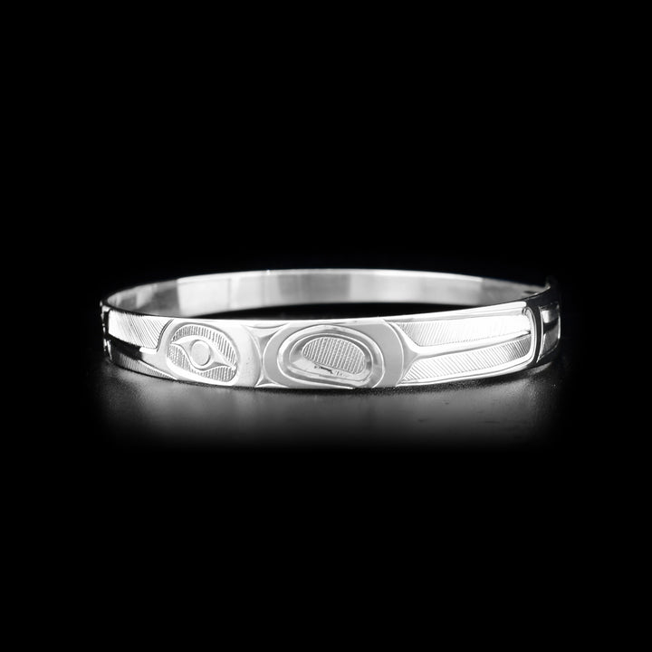 This Hummingbird bracelet is made from sterling silver and has a thin, tapered band with a clasp in the back. There are two depictions of the Hummingbird facing a flower carved into the surface of the band.