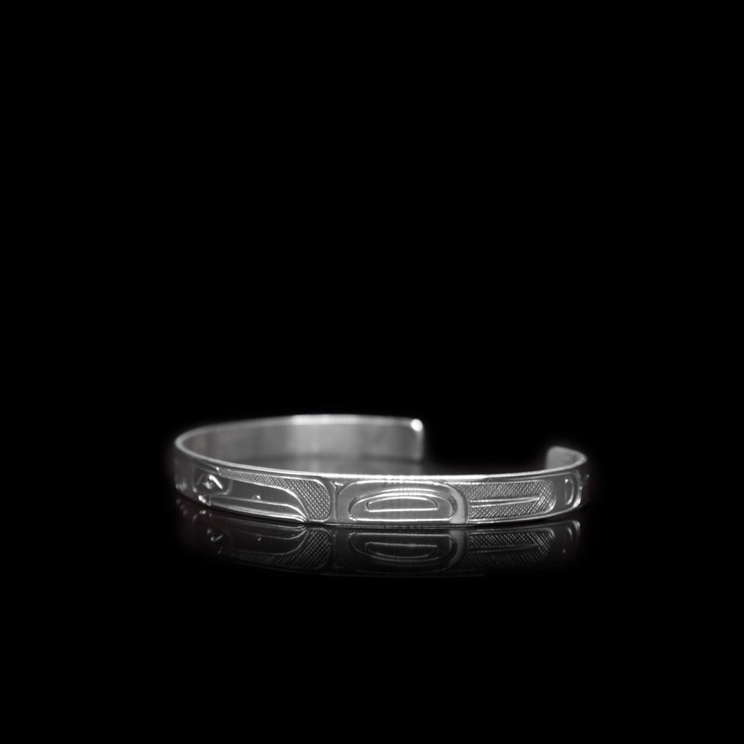 This sterling silver cuff bracelet has a thin band with depictions of the Eagle and the Raven carved into it.