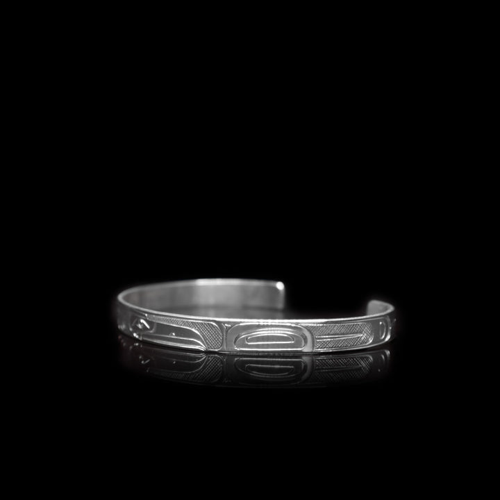 This sterling silver cuff bracelet has a thin band with depictions of the Eagle and the Raven carved into it.