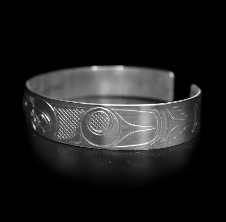 This large Eagle bracelet cuff ahs a sterling silver band with a gap in the back. there are depictions of the Eagle legend facing each other carved into the band.