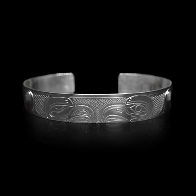 This large Eagle bracelet cuff ahs a sterling silver band with a gap in the back. there are depictions of the Eagle legend facing each other carved into the band.