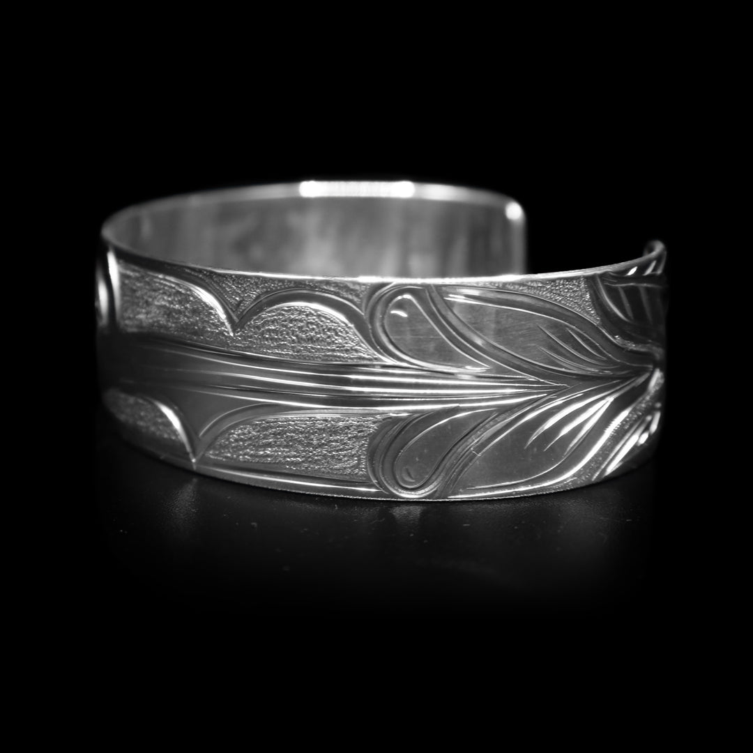 This Hummingbird bracelet has a wide, sterling silver band with a gap in the back. There is a depiction of the Hummingbird carved into the band.