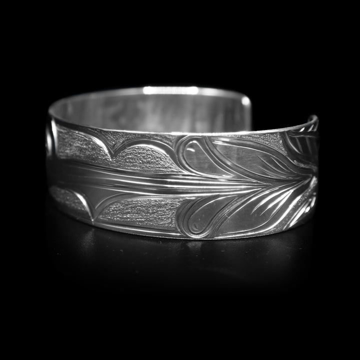 This Hummingbird bracelet has a wide, sterling silver band with a gap in the back. There is a depiction of the Hummingbird carved into the band.