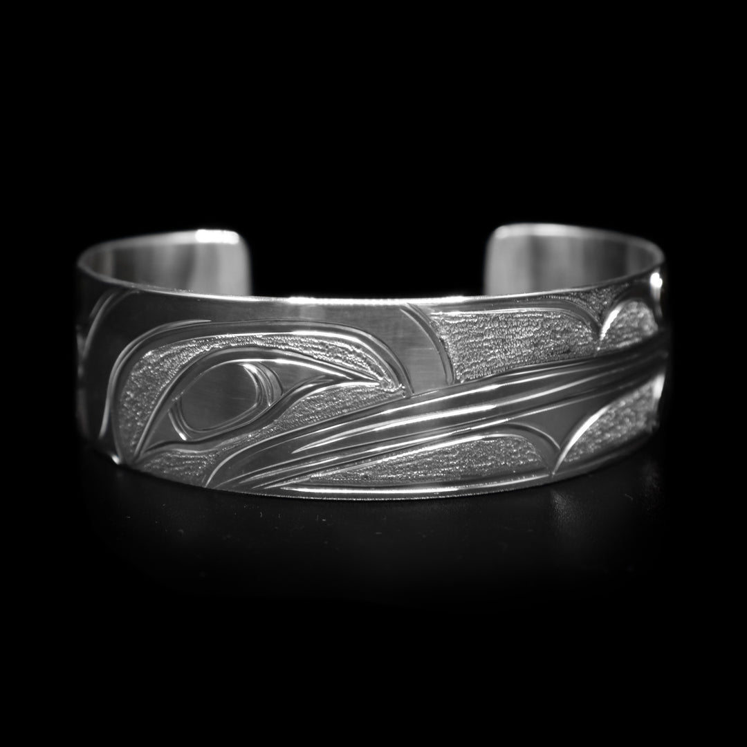This Hummingbird bracelet has a wide, sterling silver band with a gap in the back. There is a depiction of the Hummingbird carved into the band.