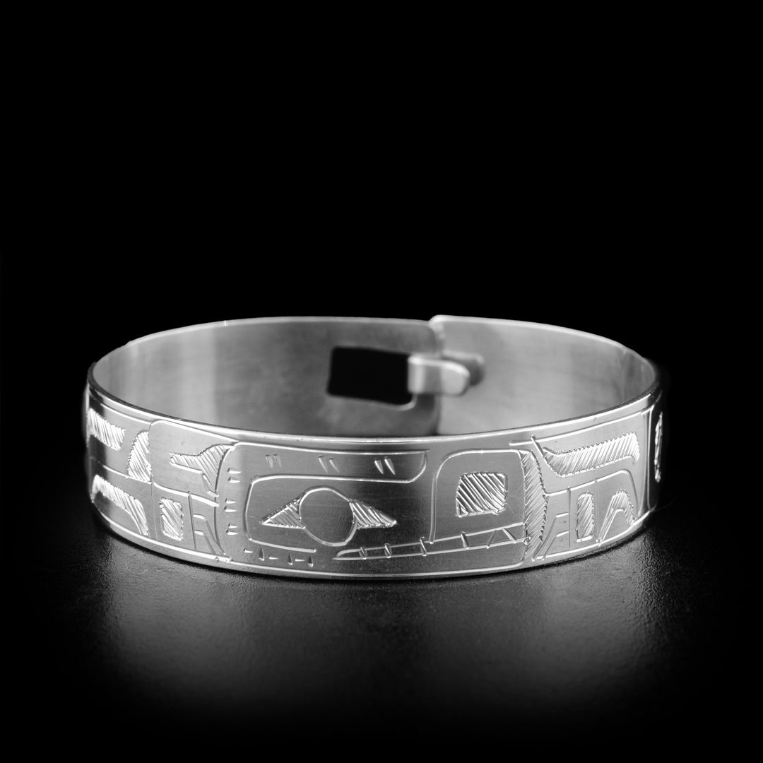 Baby's silver bracelet has a single, wide band with a clasp in the back. There is a depiction of the Bear carved into the band.