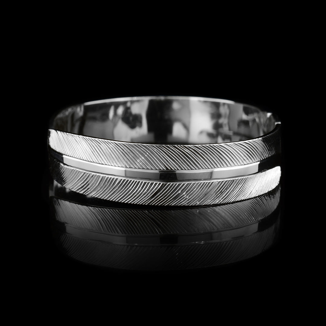 This feather cuff bracelet has a thin sterling silver band with a gap in the back. There are carvings depicting the head of the Eagle in the center of the cuff and intricate carvings depicting its feathers extending along the rest of the band.