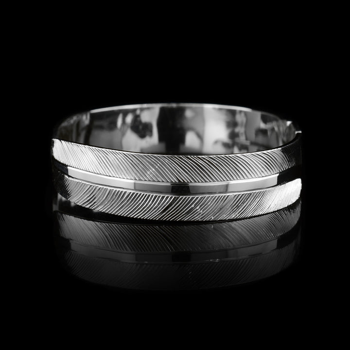 This feather cuff bracelet has a thin sterling silver band with a gap in the back. There are carvings depicting the head of the Eagle in the center of the cuff and intricate carvings depicting its feathers extending along the rest of the band.
