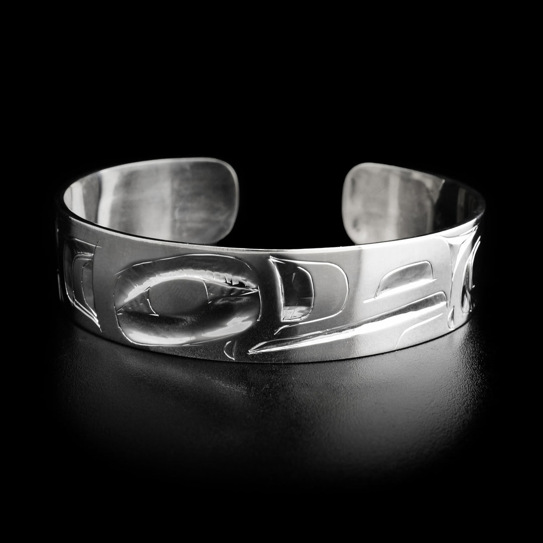 This raven bracelet has the head of a raven facing the right in the center with a long, wide beak. To the left and right are carved designs representing its feathers.