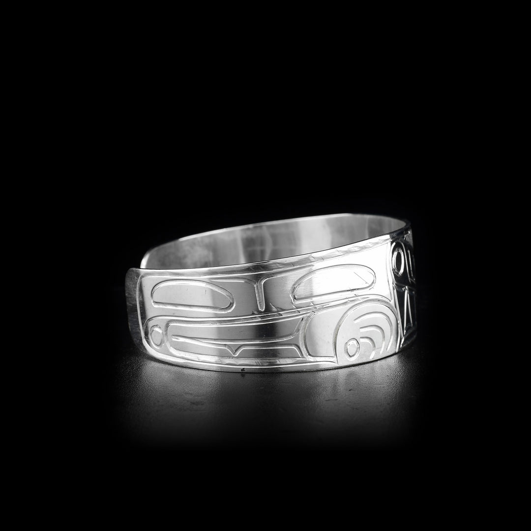 This sterling silver cuff bracelet is wide and has carvings that depict the Wolf on its surface. The band of the cuff is slightly tapered at the end.