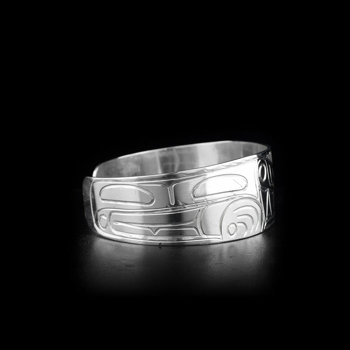 This sterling silver cuff bracelet is wide and has carvings that depict the Wolf on its surface. The band of the cuff is slightly tapered at the end.